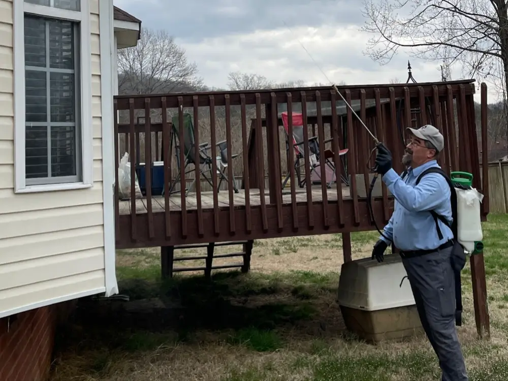 Ace Exterminating technician spraying the side of a house with pesticide in Middle Tennessee