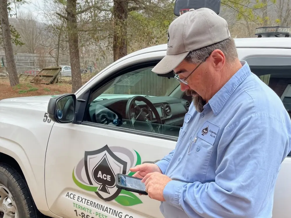 Ace Technician checking cellphone device for Pest Control appointment information in Middle Tennessee